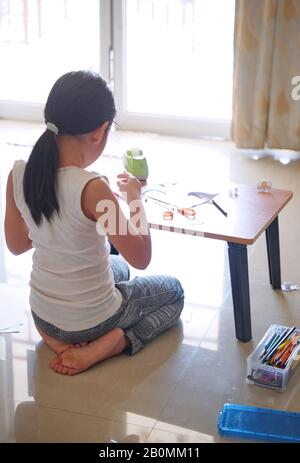 Une fille assise et faisant de l'artisanat Banque D'Images