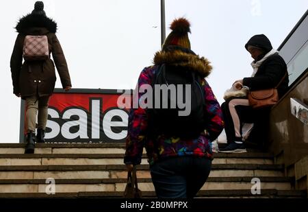 Bucarest, Roumanie - 28 janvier 2020: Les gens passent par un panneau sur lequel il est écrit vente est vu dans une rue à Bucarest. Banque D'Images