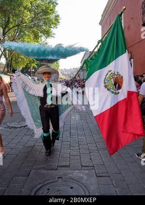 Tlaxcala de Xicohténatl, Mexique, 20 février 2020. Membre d'une Camada Charros de Huehue agitant le drapeau mexicain pendant le défilé d'ouverture du Carnaval de 2020 dans la rue de la capitale de l'État. Banque D'Images