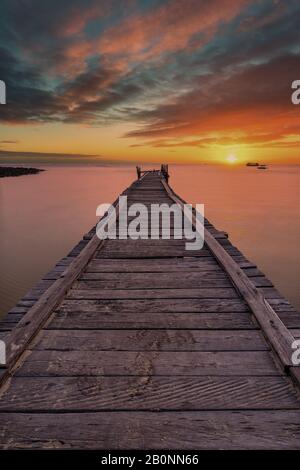 Ancienne jetée en bois s'étendant sur la mer avec un coucher de soleil spectaculaire. Banque D'Images