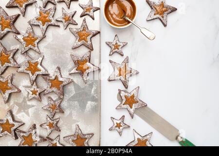 Biscuits linzer au caramel maison. Biscuits sandwich au chocolat et au caramel avec sucre glace sur fond blanc Banque D'Images