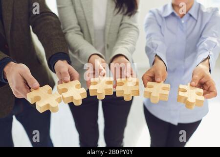 Crochez des personnes formelles montrant des pièces de puzzle en bois Banque D'Images