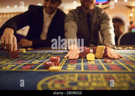 Gros plan sur les mains de personnes posant des jetons sur la table de roulette dans le casino. Banque D'Images