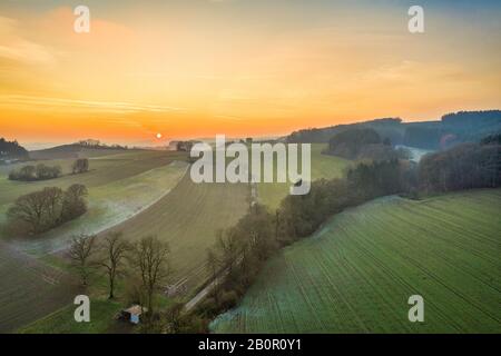 Vue large sur une vallée idyllique avec des prés et des arbres, par une journée froide et verglacée au coucher du soleil dans le Sauerland, Allemagne Banque D'Images