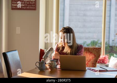 Femme enregistrant podcast dans sa cuisine Banque D'Images