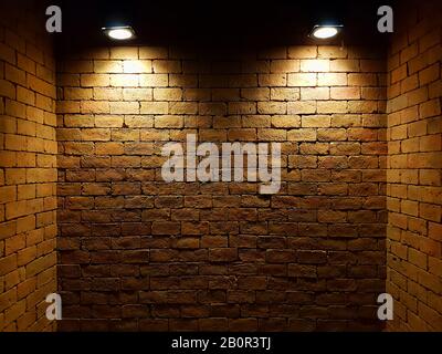 mur de briques vieux abstrait dans l'obscurité avec deux projecteurs, ton clair chaud. mur de briques dans la pièce vide. fond de mur de briques pour le papier peint Banque D'Images