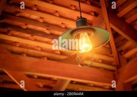 Ampoule à incandescence suspendue du plafond au-dessus de la tête depuis le toit du coin pignon de maison à la campagne asiatique. Ampoule à incandescence, style ancien et faible t Banque D'Images