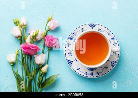 Tasse de thé aux fleurs roses eustoma sur fond bleu. Vue de dessus. Banque D'Images