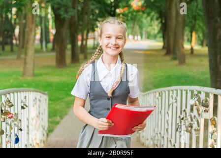 Portrait d'un élève adolescent en uniforme avec un sac à dos, dans un parc près d'un grand arbre. lycéenne en lisant un livre Banque D'Images