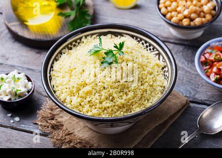 Couscous dans un bol avec l'huile d'olive. Fond de bois. Close up. Banque D'Images