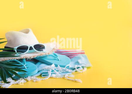 Chapeau de soleil de paille de plage, serviette, accessoires sur fond jaune. Vacances d'été arrière-plan.gros plan. Espace pour le texte. Banque D'Images