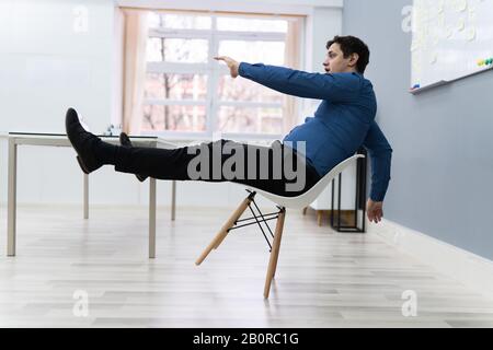 Photo De L'Homme Tombant Sur La Chaise Au Bureau Banque D'Images