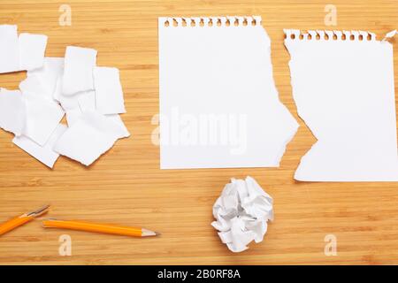 Tampon à note blanc sur une table en bois. Autour des blocs-notes se trouve beaucoup de papier froissé Banque D'Images