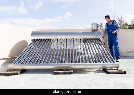 Plombier Mâle Faisant L'Inspection De La Chaudière À Énergie Solaire Banque D'Images