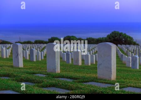 Tombales blanches du cimetière en soirée. Cimetière américain de guerre à point Loma, San Diego, Californie, États-Unis avec des rangées de pierres tombales Banque D'Images