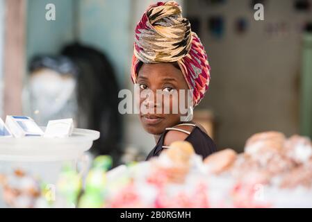 Vendeur mûr assis derrière son stand de bonbons regardant la caméra. Banque D'Images