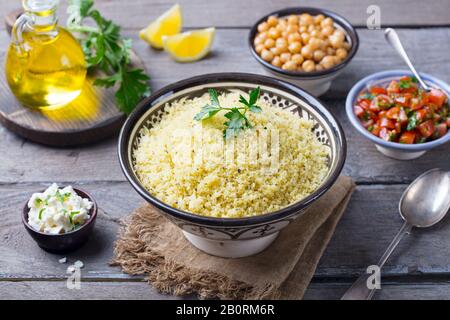 Couscous dans un bol avec l'huile d'olive. Fond de bois. Close up. Banque D'Images