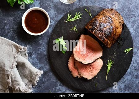 Bœuf grillé en tranches à bord de bois sur fond de pierre bleue. Rôti de bœuf moyen et rare. Vue sur le dessus, plat Banque D'Images