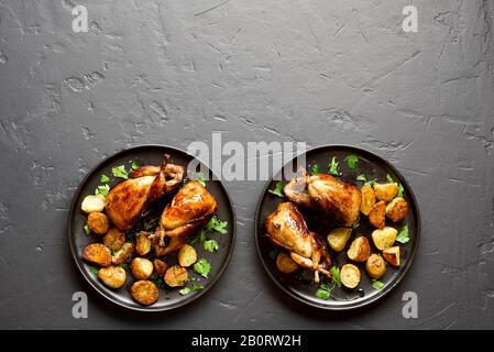 Délicieuses carcasses de cailles grillées avec pommes de terre cuites sur fond de pierre noire avec espace libre pour le texte. Quails rôtis sur plaque. Vue sur le dessus, plat Banque D'Images