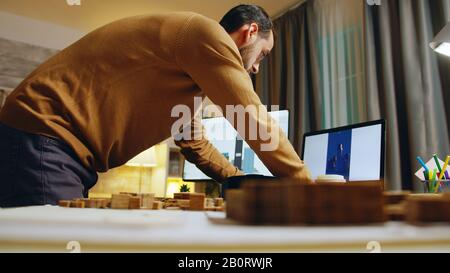 Architecte masculin travaillant la nuit dans son bureau à la maison pour terminer le nouveau projet de construction pour les investisseurs. Banque D'Images