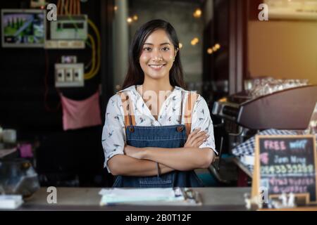 Asian women smiling Barista et à l'aide d'une machine à café dans le café au comptoir - femme au travail propriétaire de petite entreprise nourriture et boisson cafe concept Banque D'Images