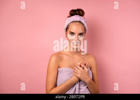 Une fille avec un bandage sur la tête et des correctifs sous ses yeux se dresse sur un fond rose avec ses mains sur sa poitrine. Banque D'Images