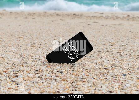 Spartphone avec texte numérique detox écrit dans son écran placé dans le sable d'une plage. Médias sociaux gadget Internet dépendance concept Banque D'Images