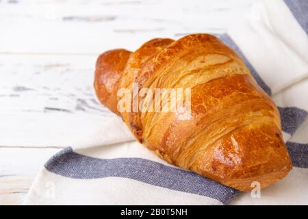 Croissant de rosy français sur serviette claire sur fond blanc. Concept de boulangerie. Banque D'Images