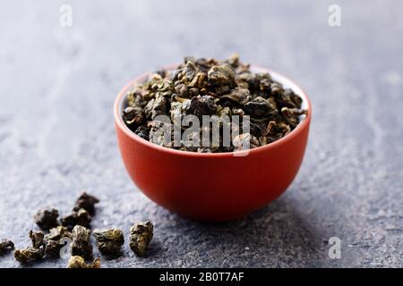 Thé vert oolong dans un bol de tasse à thé en argile. Fond en pierre grise. Gros plan. Banque D'Images