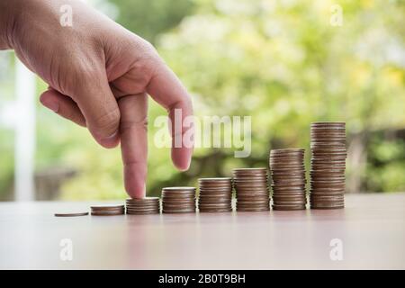 Les doigts marchent sur la pile de pièces ou la pile d'argent Banque D'Images