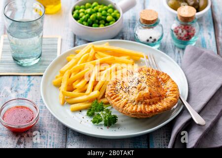 Tarte à la viande avec frites sur une plaque blanche. Fond en bois. Gros plan. Banque D'Images