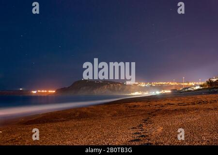 Empreintes de pas menant à la petite Foggy Tono Bay ou Baia del Tono. Photo prise de la plage de Milazzo. Effet de soie dans la mer et la brillance de certaines étoiles i Banque D'Images