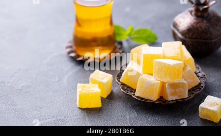 Le plaisir turc sur une plaque de cuivre avec un verre de thé. Fond en pierre grise. Espace de copie. Banque D'Images