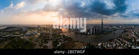 Vue panoramique spectaculaire sur la rivière Saigon et les gratte-ciel d'Ho Chi Minh City au coucher du soleil avec de beaux ormes et des nuages aux couleurs vives dans le ciel Banque D'Images
