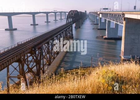 Benicia California, un vieux pont ferroviaire rouillé au premier feu. Rouille, béton et acier une grande juxtaposition de nouveau contre ancien. Banque D'Images