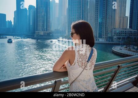 Happy tourist femme en robe blanche d'été à la mode à la marche et faire dans la marina de Dubaï en Émirats Arabes Unis. Luxe et confort t Banque D'Images