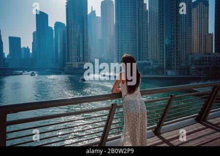 Happy tourist femme en robe blanche d'été à la mode à la marche et faire dans la marina de Dubaï en Émirats Arabes Unis. Luxe et confort t Banque D'Images