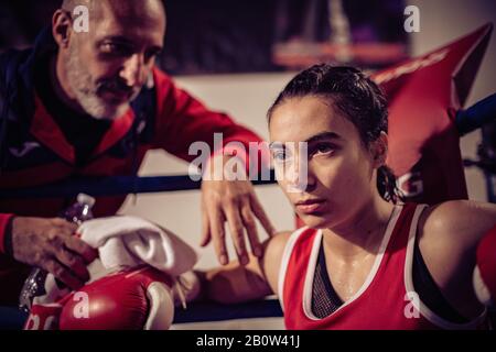 Portrait de l'entraîneur de boxe et du boxeur féminin assis dans la bague de boxe. Banque D'Images