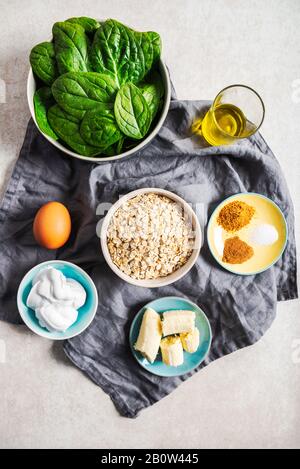 Ingrédients pour des crêpes vertes saines comme les épinards, le lait de coco, la banane, l'oeuf et l'avoine. Petit-déjeuner végétarien et sans gluten Banque D'Images