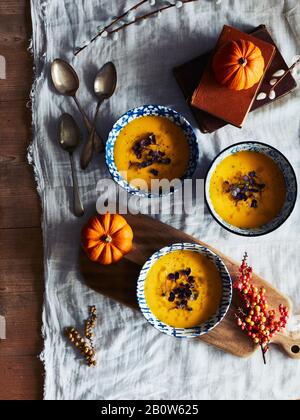 Grand angle, gros plan de citrouilles orange et bols de soupe de citrouille sur une table. Banque D'Images