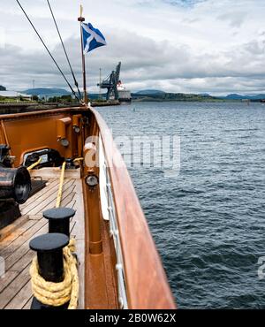 Drapeau écossais à l'arc du bateau à vapeur de Paddle Waverley avec le bateau à cunard la Reine Elizabeth au loin à Greenock sur le Clyde Banque D'Images