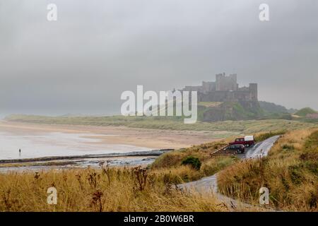 Un déambulateur de pluie vous permet d'explorer une plage vide dans un petit matin drizzli surmoulé. Banque D'Images