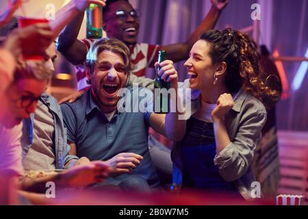 De jeunes amis heureux buvant de la bière et heureux pour leur équipe de football pendant que vous regardez un match à la télévision Banque D'Images