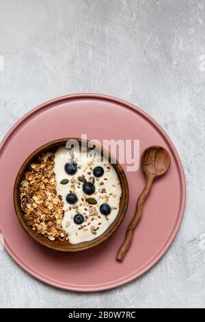 Bol de muesli et bleuets au yaourt, cuillère à café en bois Banque D'Images