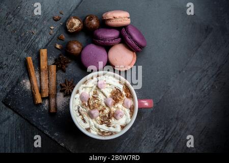 Chocolat chaud recouvert de guimauves et crème, macarons, bâtons de cannelle, anis étoilé Banque D'Images