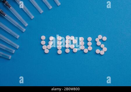 Pilules et seringues sur fond bleu clair. Propagation du coronavirus. Infection virale. Concept médical. Banque D'Images