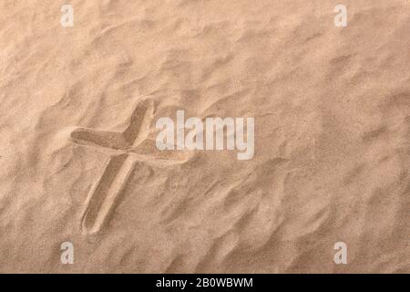 Croix comme symbole religieux gravé dans le sable. Composition horizontale Banque D'Images