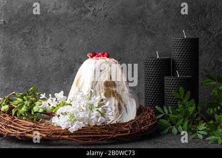 Fromage blanc cottage gâteau de pâques au kulich dans la tradition orthodoxe, fleurs blanches, bougies noires, plumes, couronne en osier sur fond sombre, IMA horizontal Banque D'Images