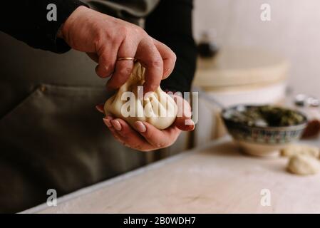 Faire cuire. Femme qui fait du khinkali pour sa famille proche. Préparer le repas traditionnel géorgien de la pâte et de la viande à la cuisine. Cuisine nationale, co Banque D'Images