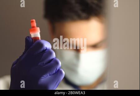 Fermeture d'un échantillon de sang détenu par le personnel du laboratoire médical en arrière-plan Banque D'Images